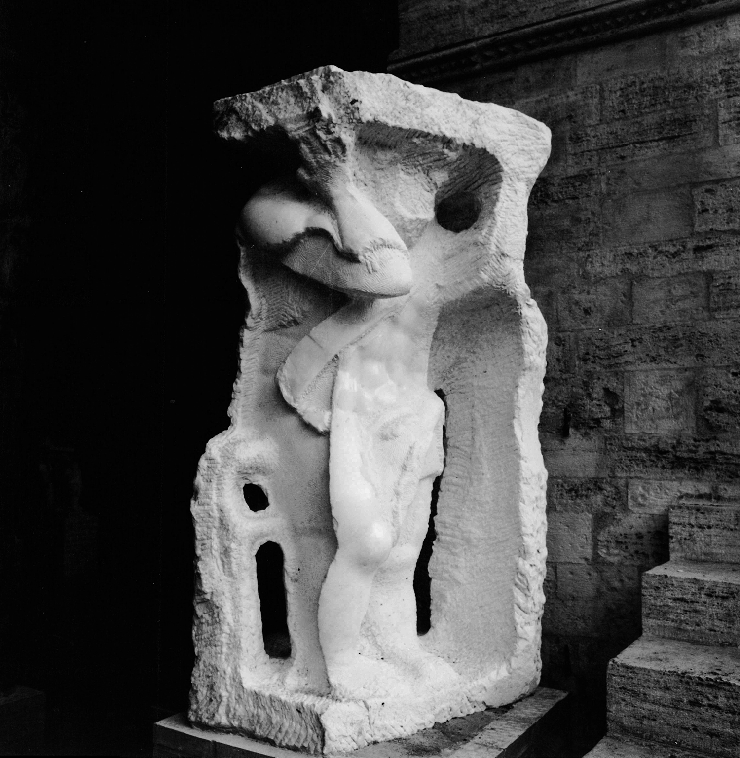 Grande scultura in marmo bianco che rappresenta un uomo che sorregge una base al di sopra della testa installata ai piedi della scalinata del Palazzo Comunale di Todi in provincia di Perugia