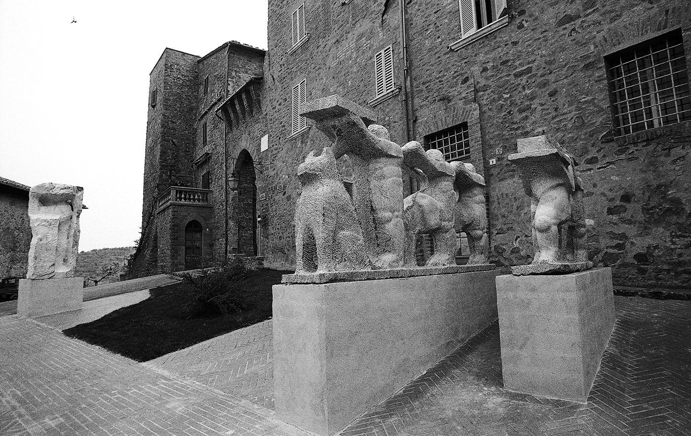 Gruppo di due sculture in marmo che rappresentano una famiglia di aborigeni con il loro dingo in mostra vicino le mura medioevali della città di Paciano in provincia di Perugia