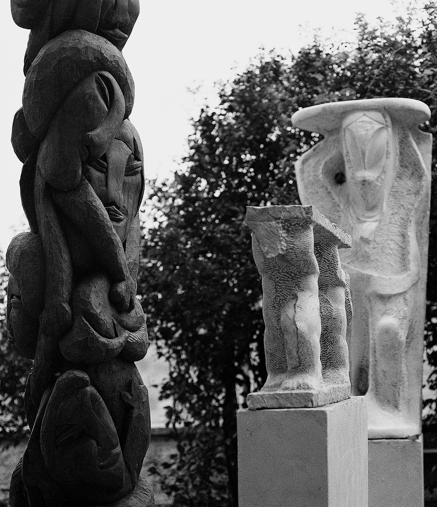 Particolare del grande totem in legno e due sculture in cui si riconoscono i volti delle figure totemiche